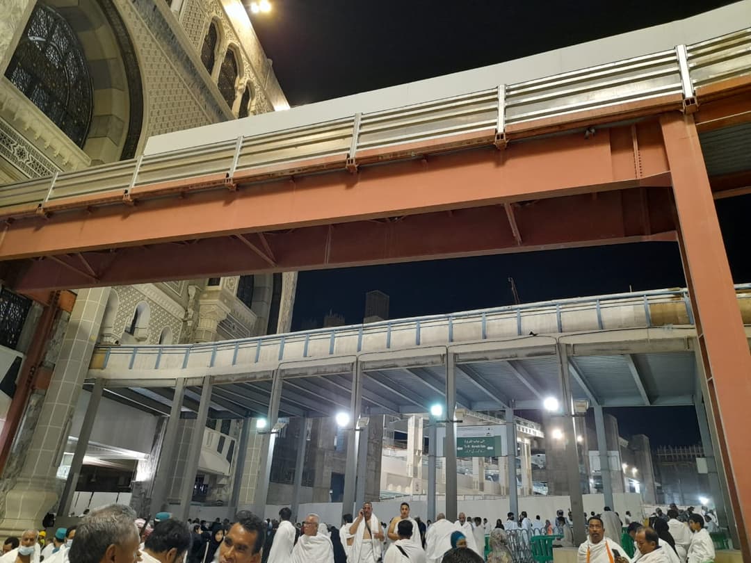 Elevated walkways and pilgrims at Masjid al-Haram at night.