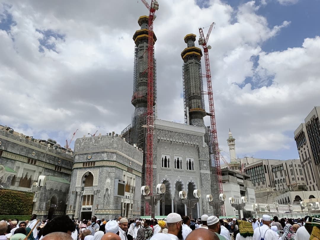 Low-angle daytime view of Masjid al-Haram minarets under construction.