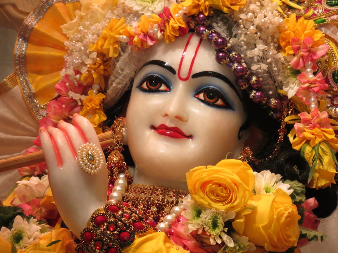 Close-up of the Krishna deity adorned with floral garlands and jewels
