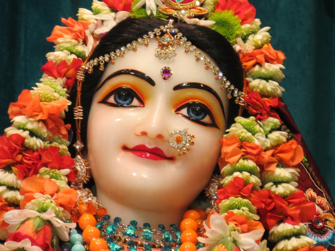 Close-up of the deity Sri Radha adorned with flowers and jewelry.
