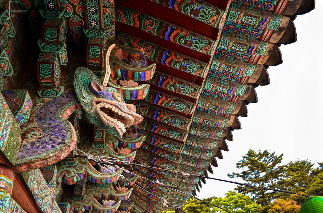 Low-angle view of a carved dragon head and Dancheong eaves at Bulguksa Temple.