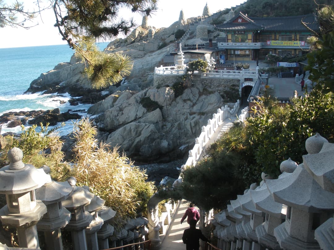High-angle view of stone lantern-lined stairs leading to the seaside temple.