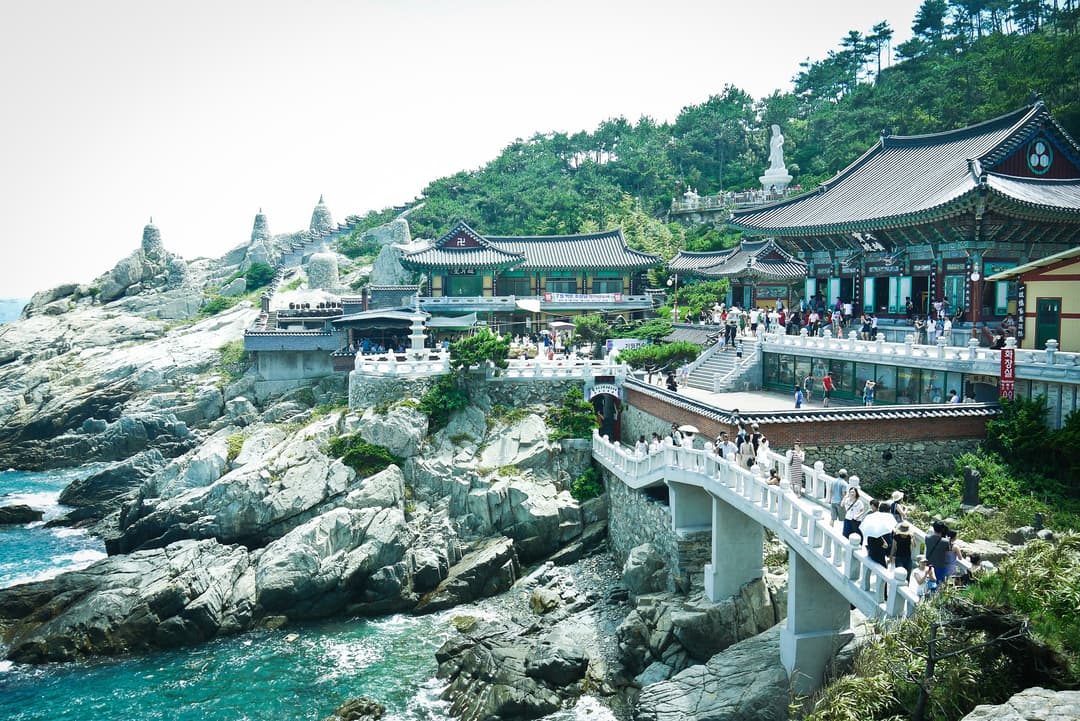 Wide-angle view of Haedong Yonggungsa Temple and bridge on coastal cliffs.