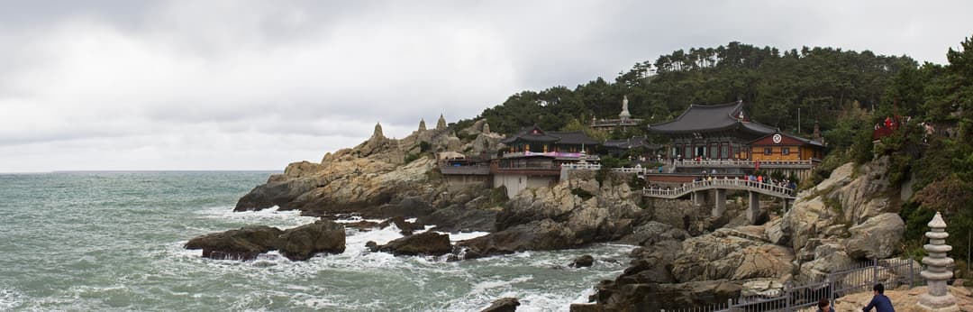 Wide panoramic view of Haedong Yonggungsa Temple built along rocky sea cliffs.