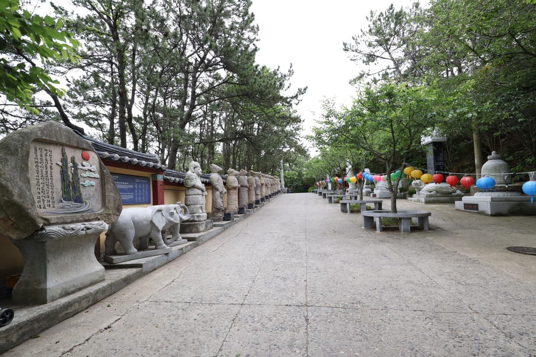 Wide-angle view of the paved pathway lined with stone zodiac statues.