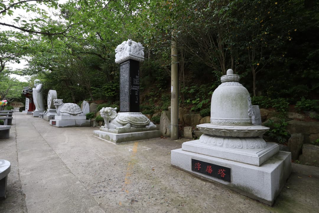 Stone stupa and turtle steles along a paved pathway at Haedong Yonggungsa.