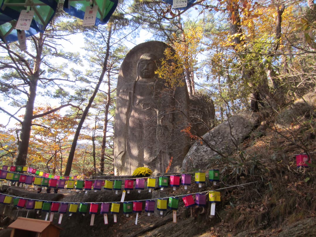 Rock-carved Standing Buddha with lanterns on the grounds of Haeinsa.