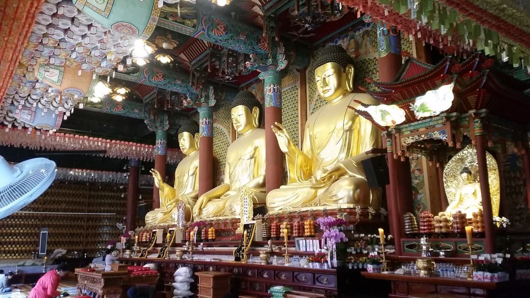 Three large golden Buddha statues inside the main hall of Jogyesa Temple.