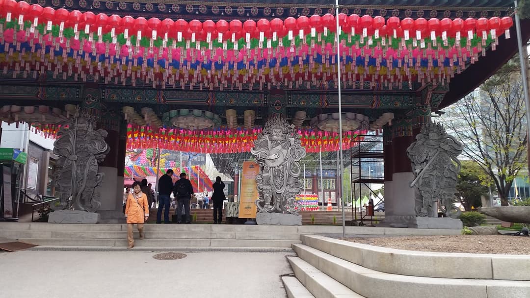 Lantern-draped entrance gate with guardian statues at Jogyesa Temple.