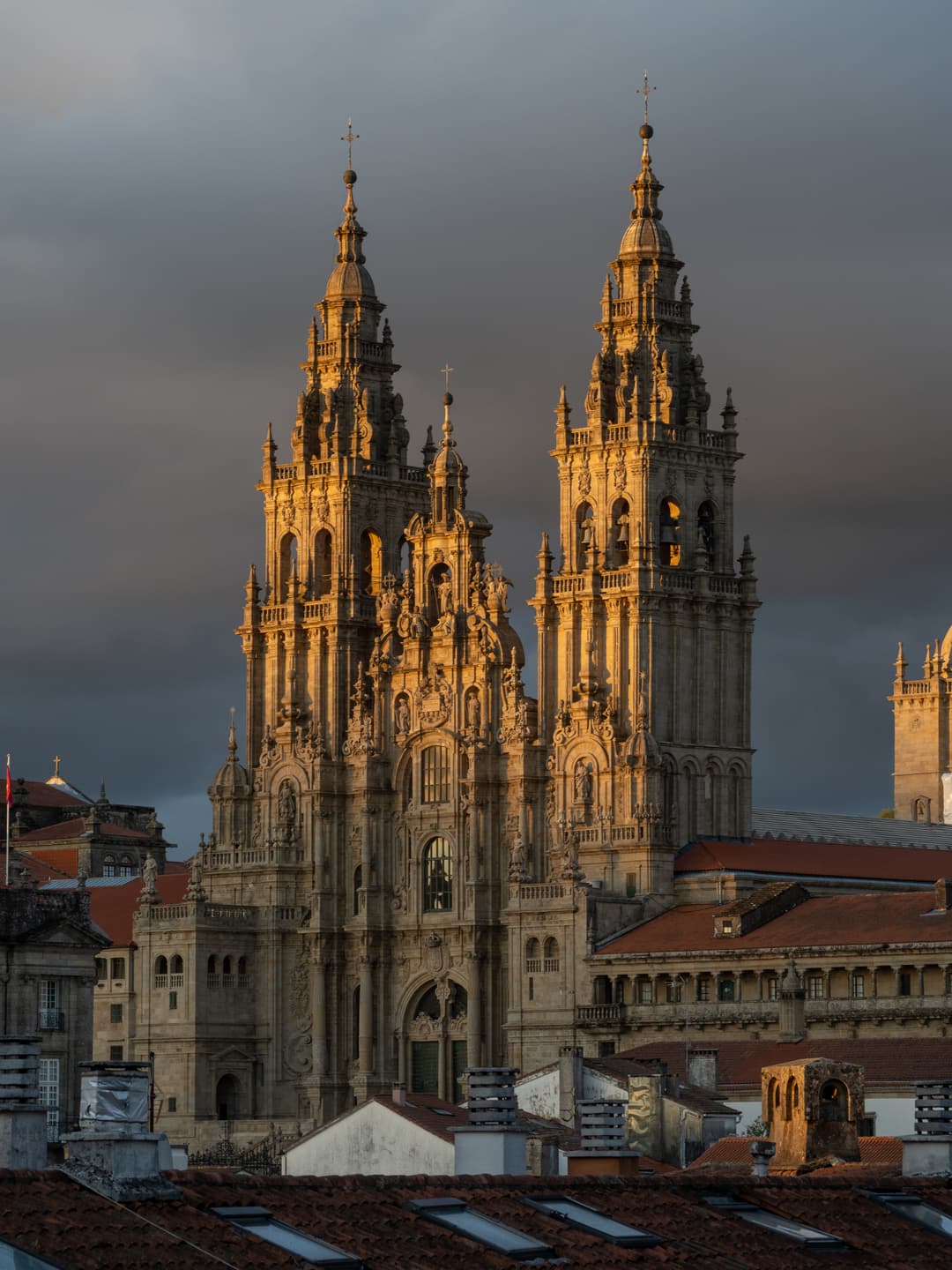 Obradoiro façade towers illuminated by golden evening light over rooftops