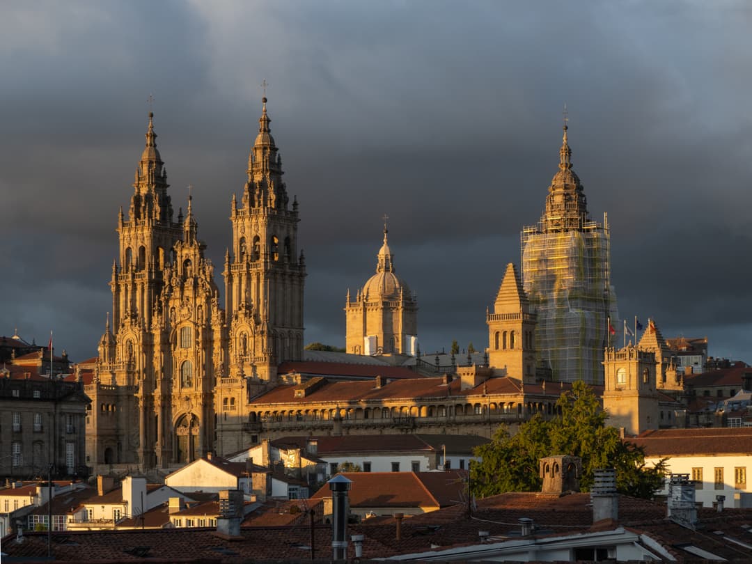 Santiago de Compostela Cathedral at golden hour beneath dark storm clouds