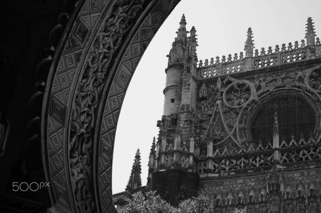 Gothic facade and pinnacles framed by an ornate archway.