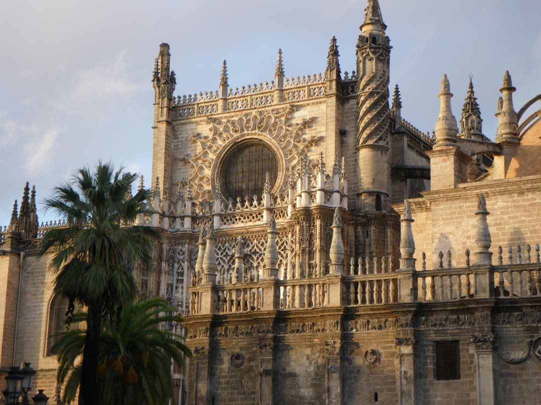 Gothic facade details, circular window, and spiral turret in evening light