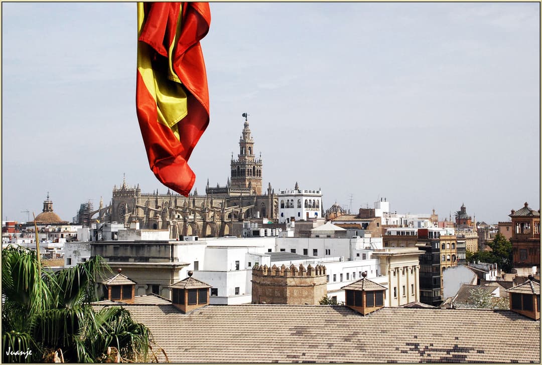 Cityscape view of Seville Cathedral and the Giralda with the Spanish flag