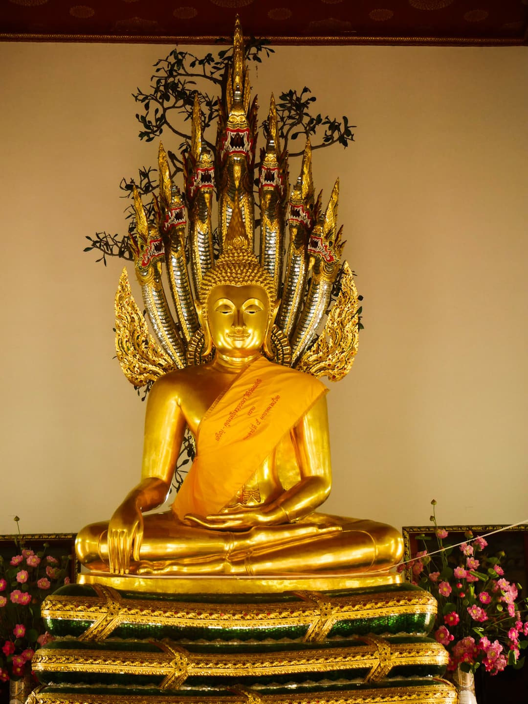 Golden Buddha statue sheltered by a multi-headed Naga serpent at Wat Pho.