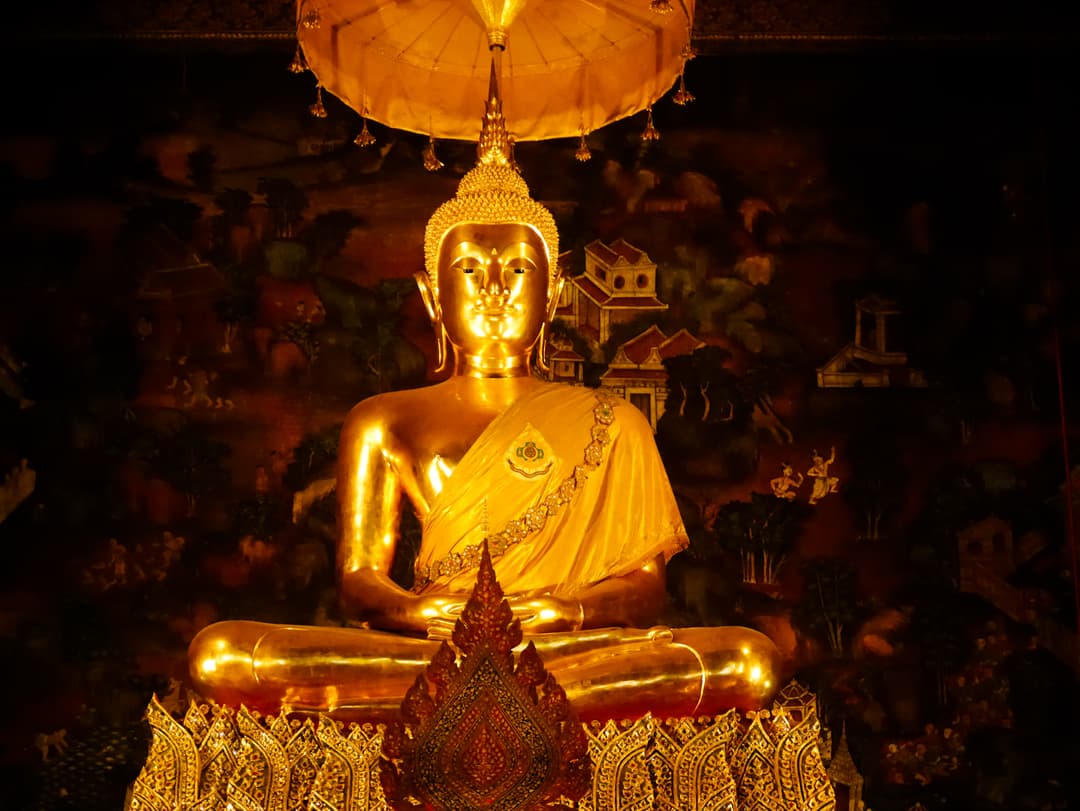 Golden seated Buddha statue inside the main ordination hall of Wat Pho.