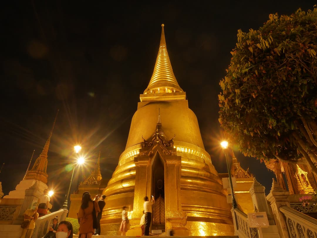 Low-angle night view of the illuminated golden chedi at Wat Phra Kaew.