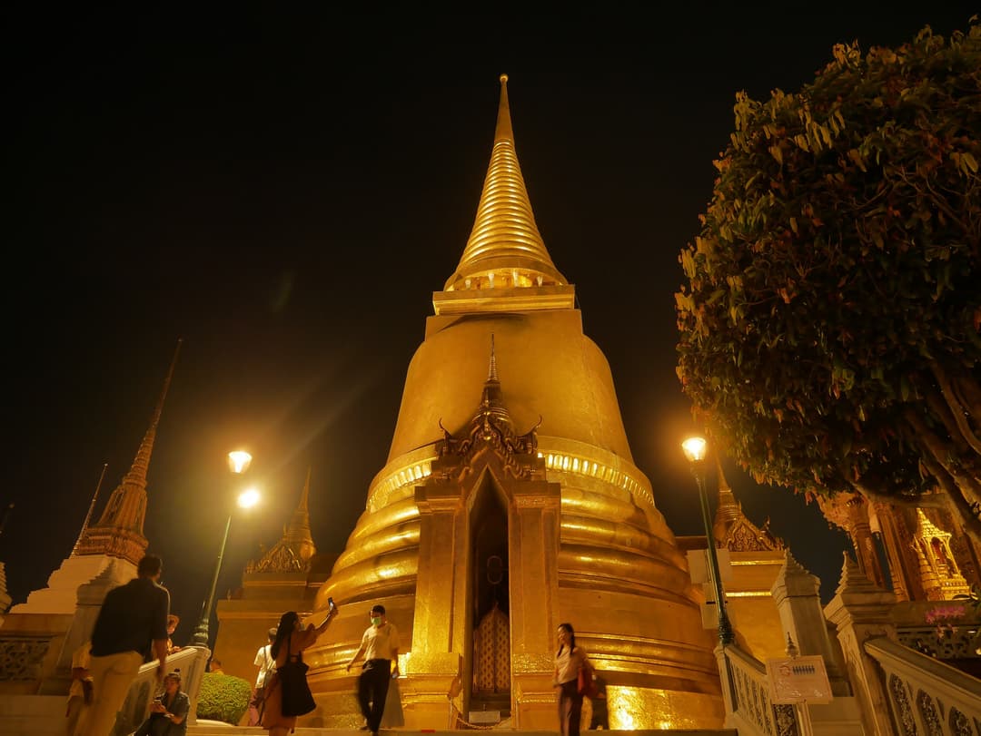 Low-angle night view of the illuminated golden stupa at Wat Phra Kaew.
