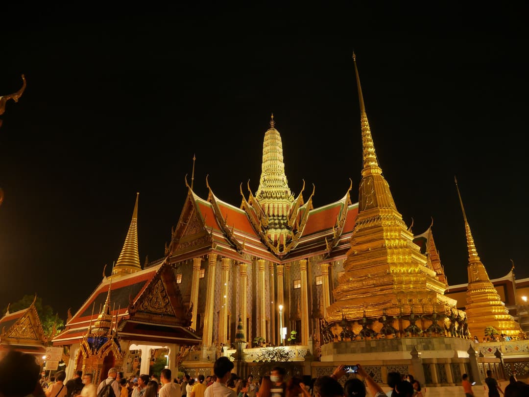 Nighttime view of the illuminated golden chedis and spires at Wat Phra Kaew.