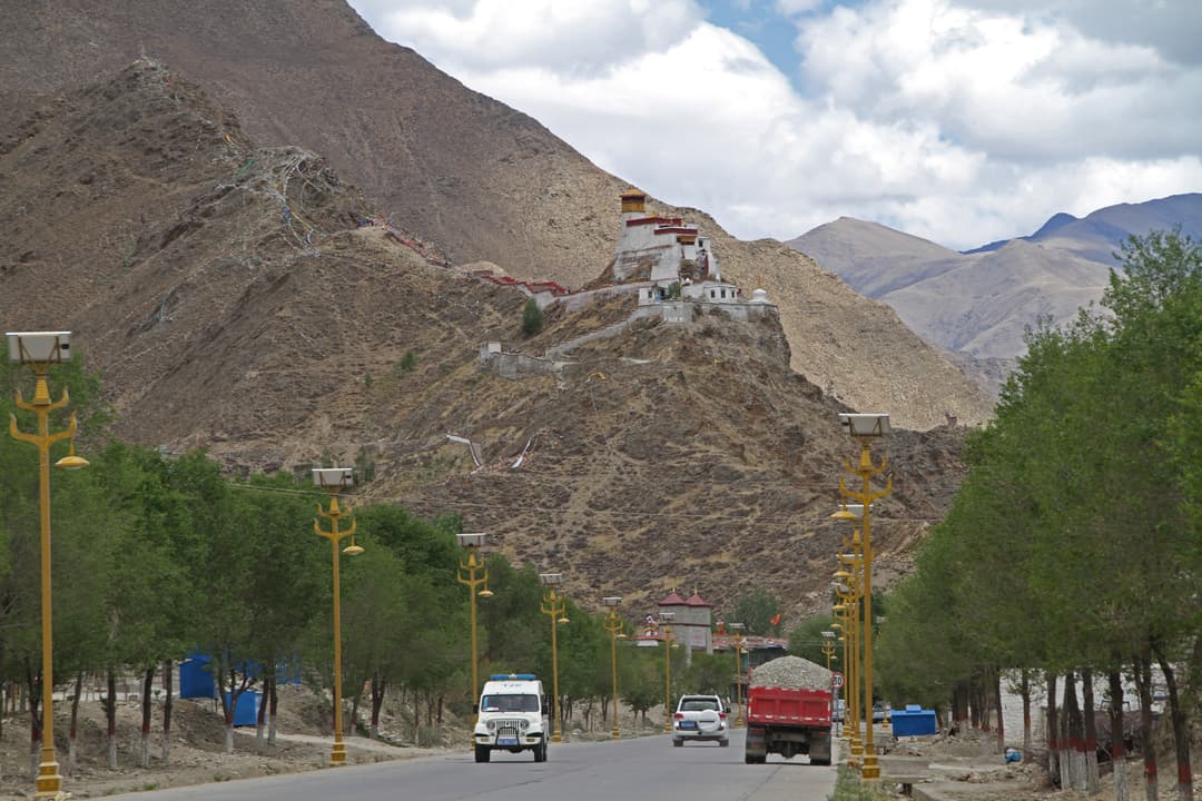 Distant view of Yumbulagang fortress from the tree-lined road approach.