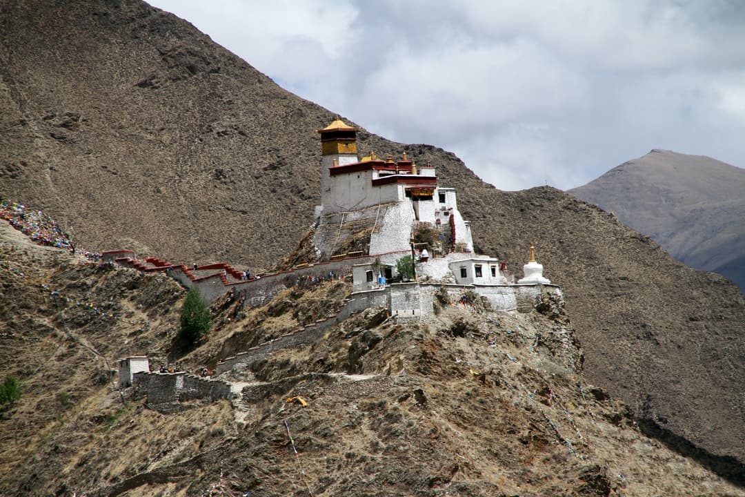 Wide-angle exterior view of Yumbulagang atop a rocky mountain ridge.