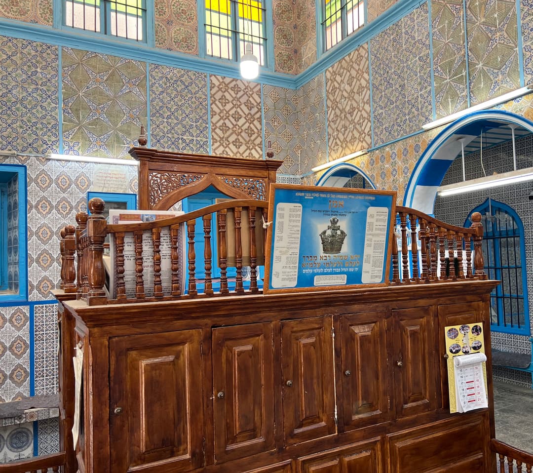 Wooden bimah and tiled walls inside El Ghriba Synagogue