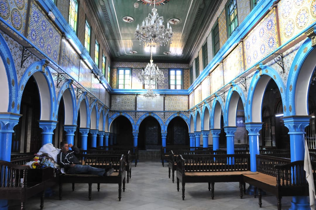 Interior of the main prayer hall with blue arches and chandeliers