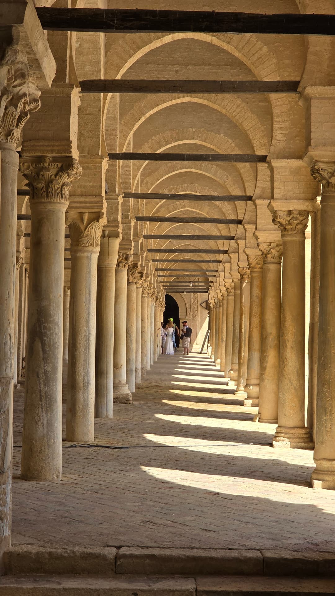 Sunlit courtyard portico with antique spolia columns and arches.