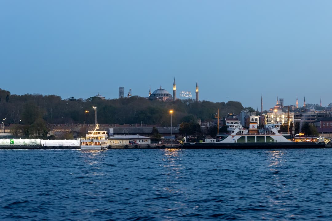 Distant view of Hagia Sophia across the water at dusk with illuminated mahya.