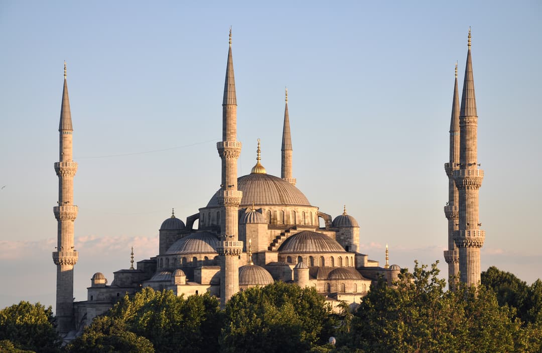 The cascading domes and minarets of Sultan Ahmed Mosque at golden hour.