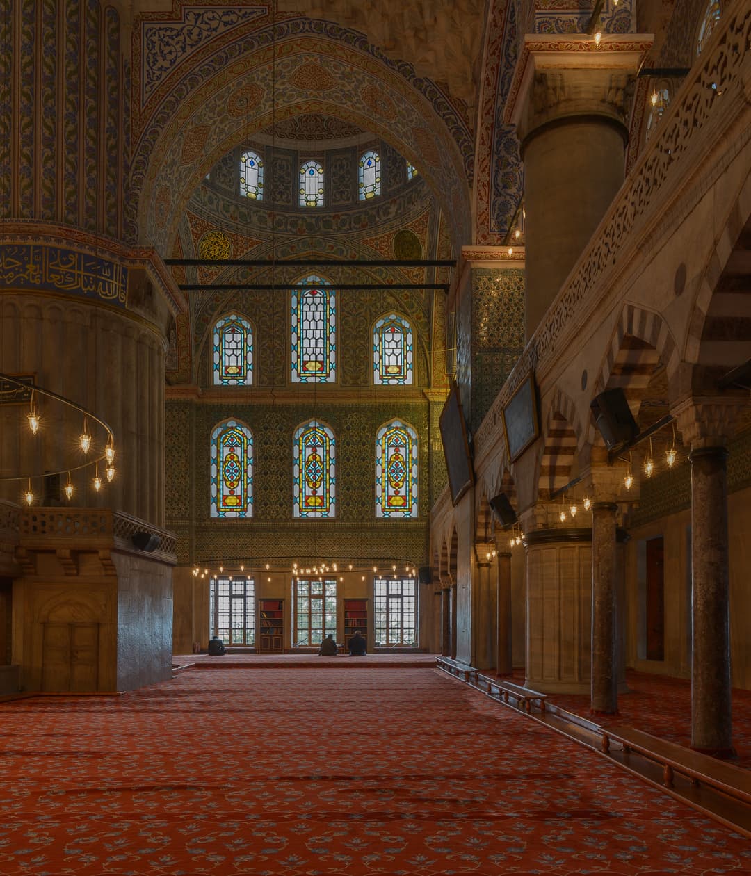 Interior of the Sultan Ahmed Mosque with stained glass windows and red carpet
