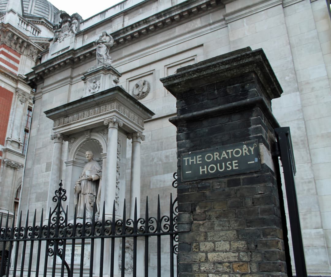 Low-angle view of gate post with Oratory House sign and Cardinal Newman statue.
