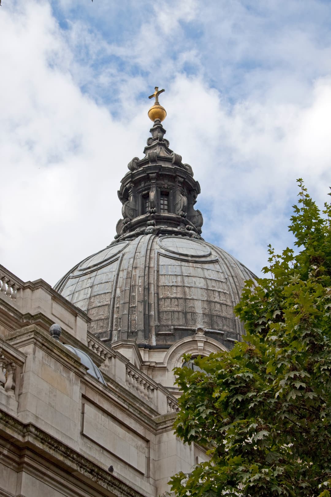 Low-angle view of the Brompton Oratory dome topped with a golden cross.