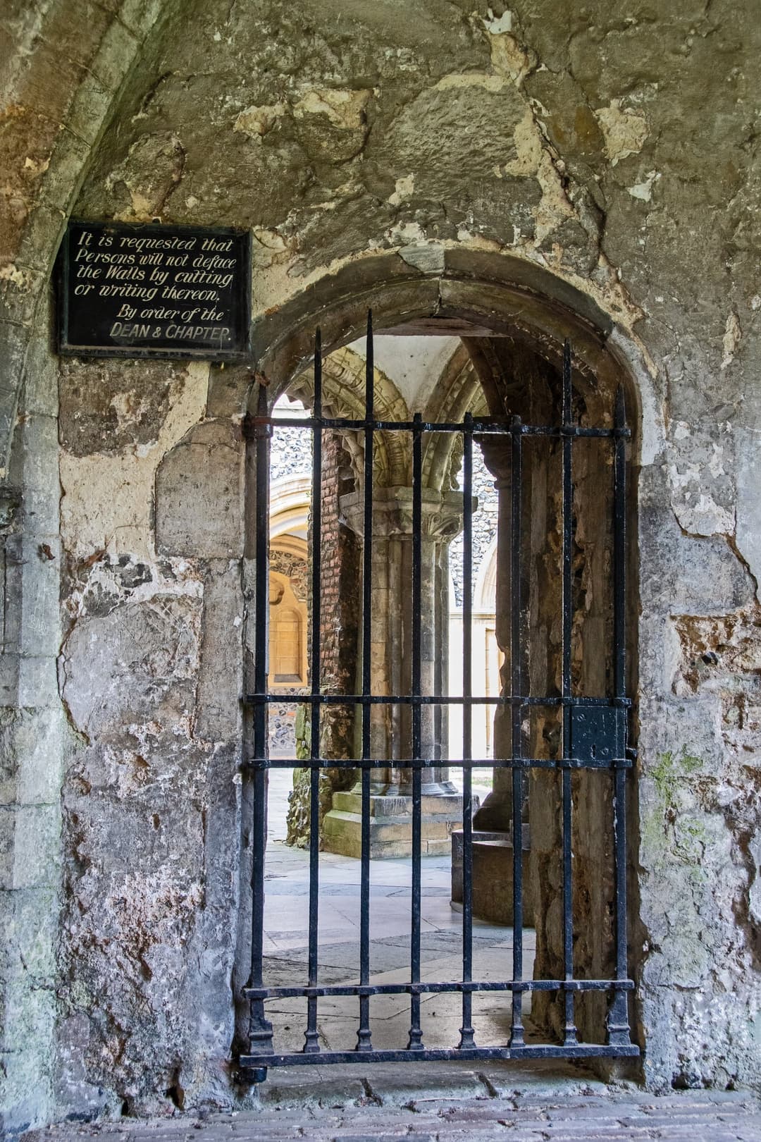 Gated archway with historic warning sign at Canterbury Cathedral
