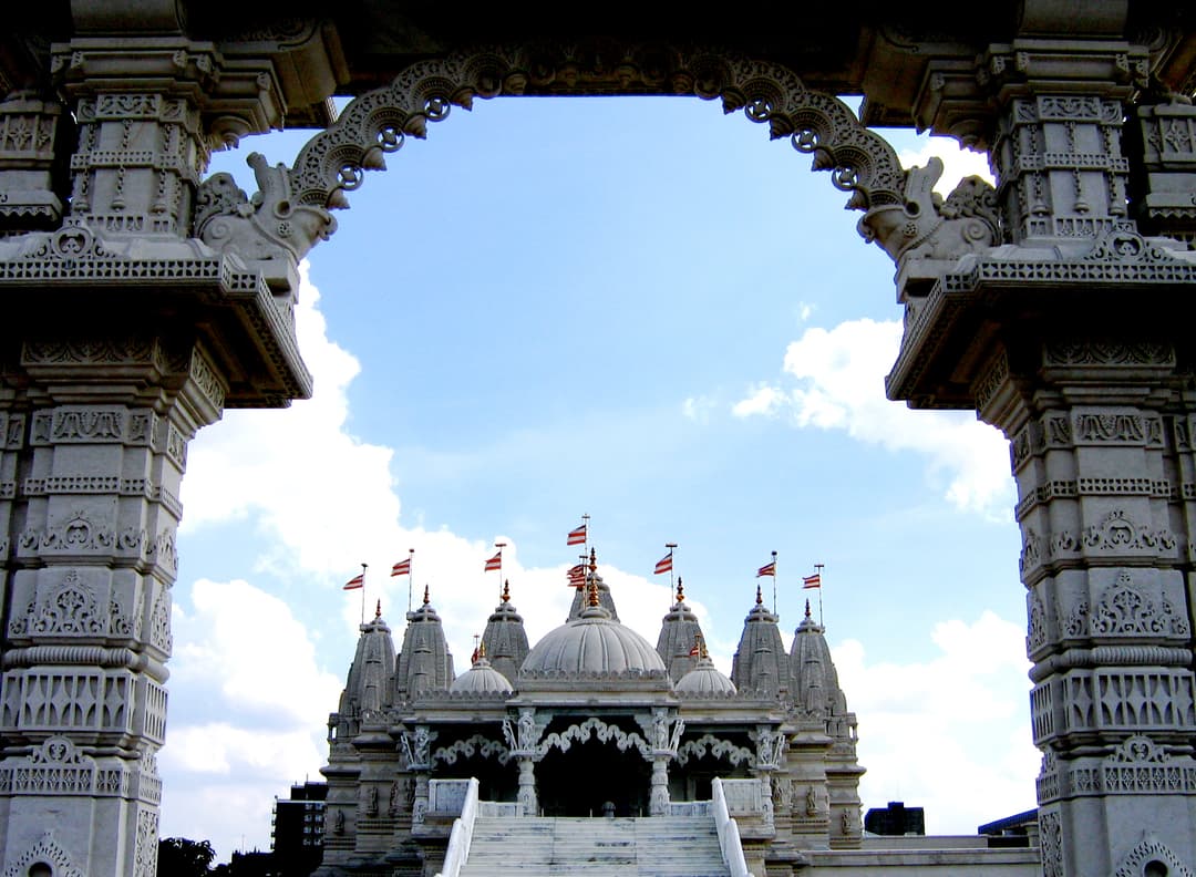 View of the BAPS Shri Swaminarayan Mandir framed by a carved stone arch.