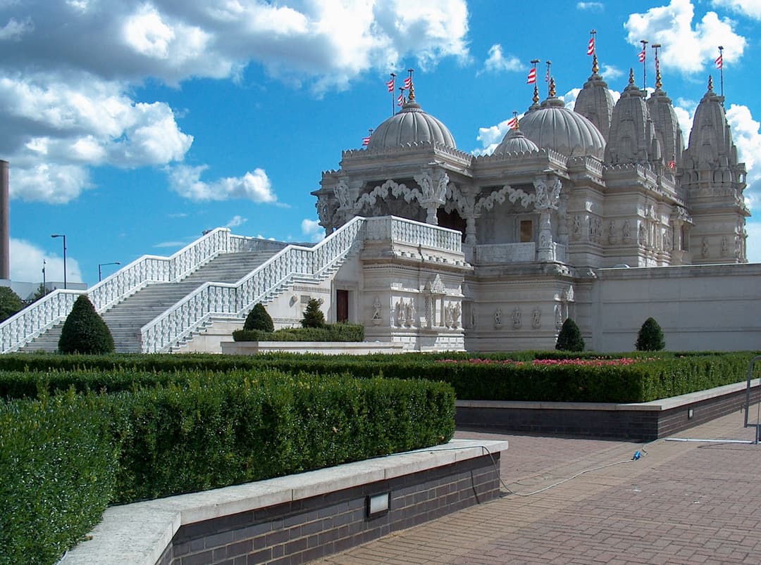 Exterior view showing the grand marble staircase, domes, and manicured gardens.