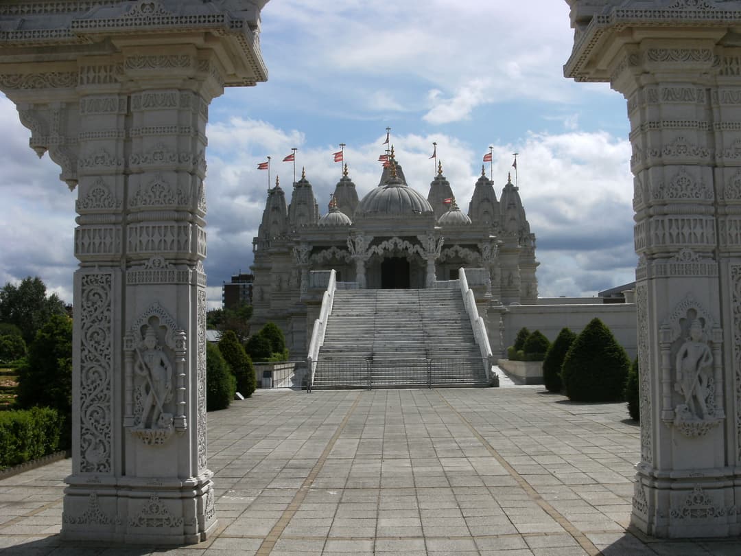 Front view of Neasden Temple's entrance framed by intricately carved pillars.
