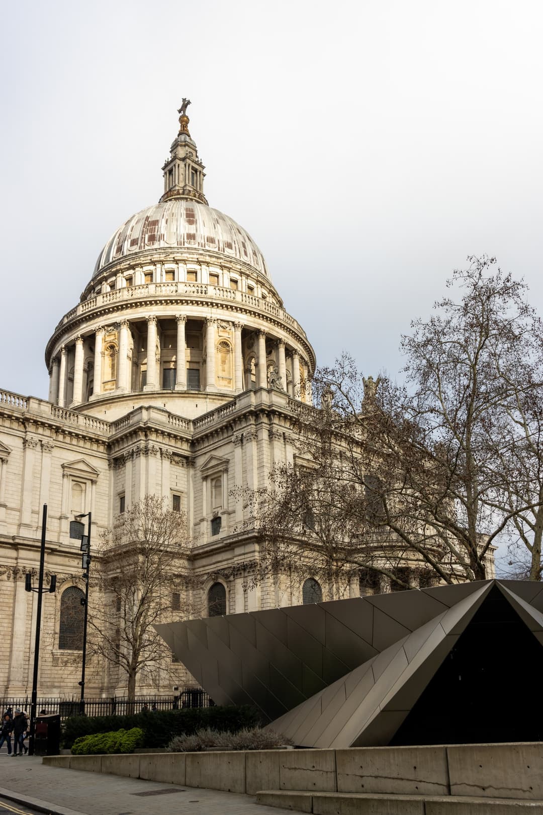 Low-angle view of St. Paul's Cathedral dome with modern pavilion in foreground.