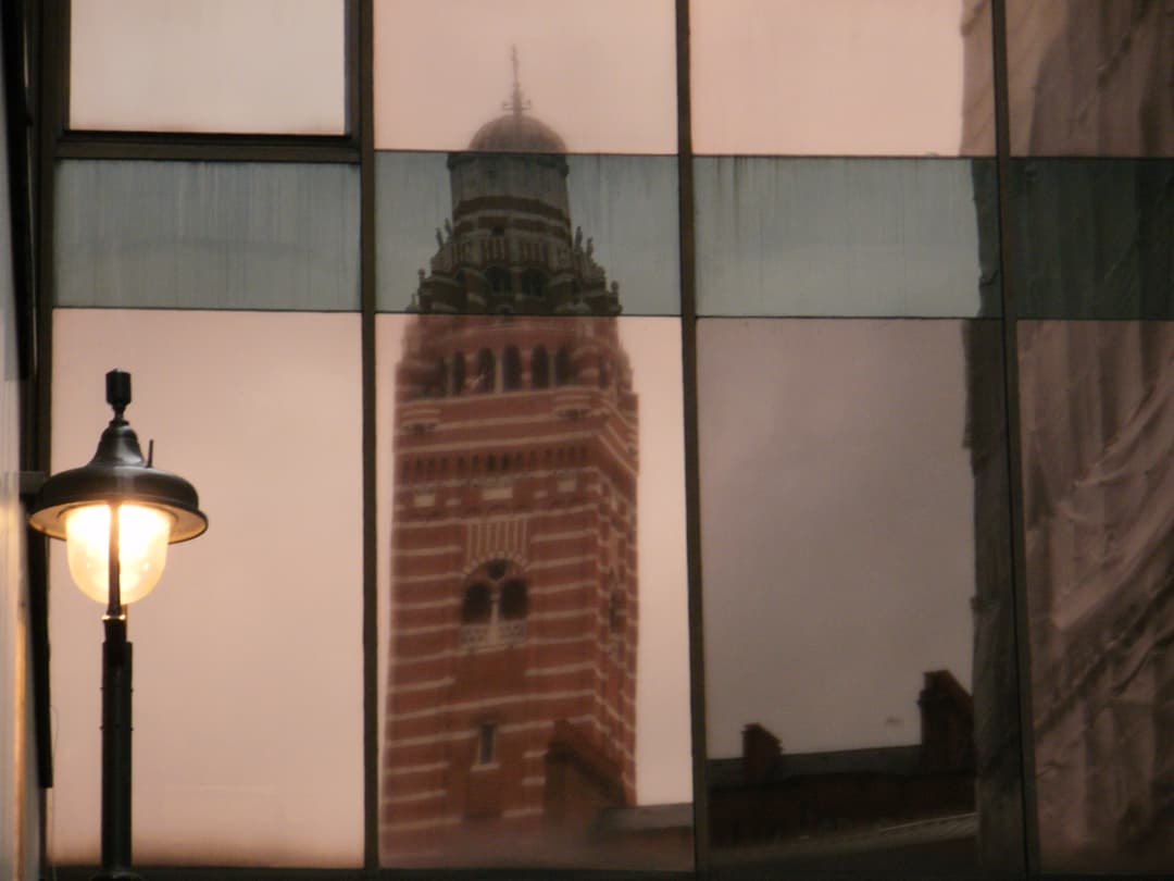 Reflection of Westminster Cathedral's campanile in a glass facade at dusk.