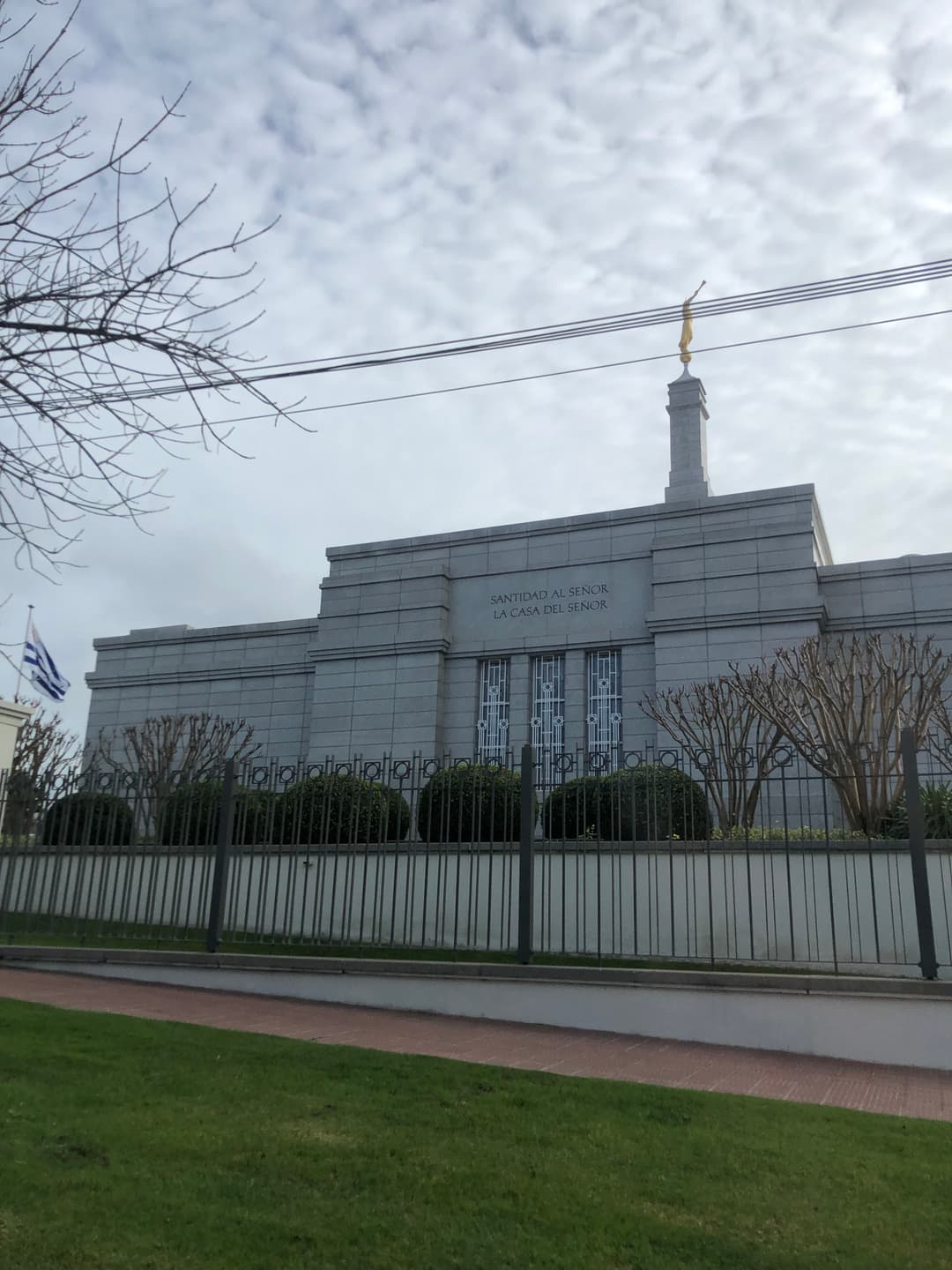 Montevideo Uruguay Temple exterior with Angel Moroni, flag, and power lines.