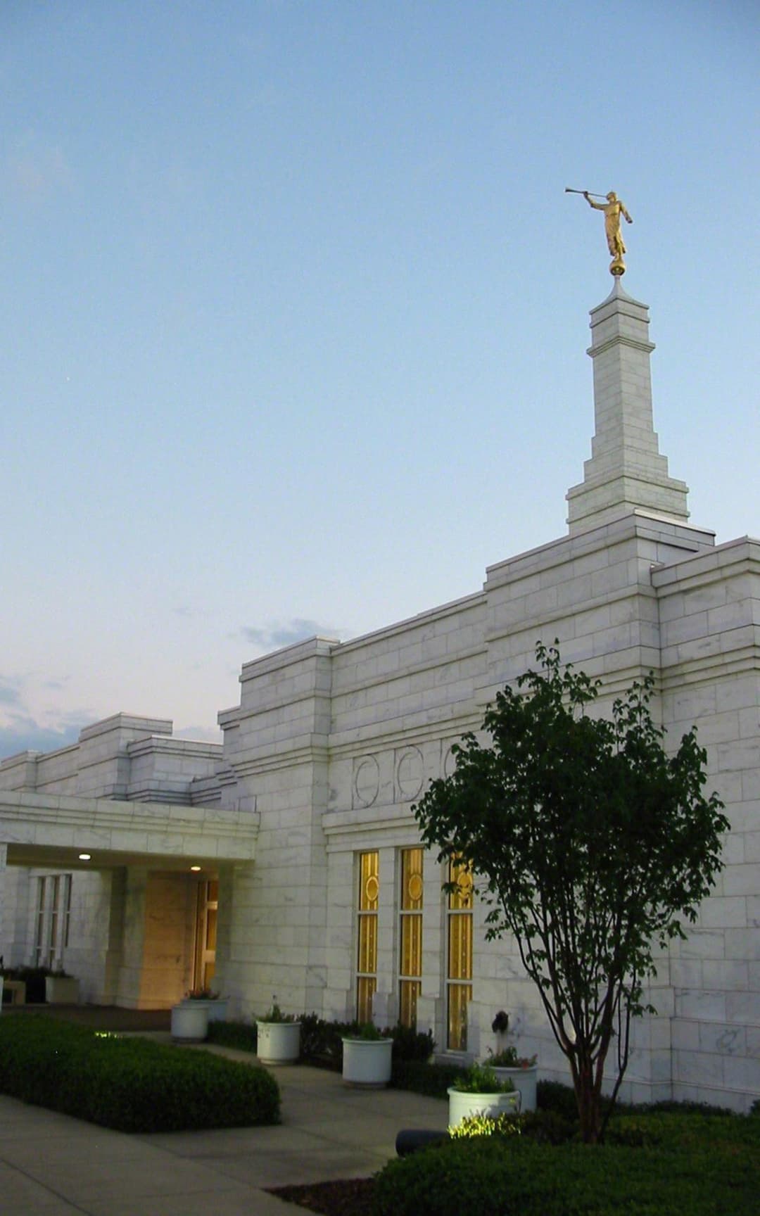 The elegant Vermont marble exterior of the Birmingham Alabama Temple nestled against a lush green hillside.