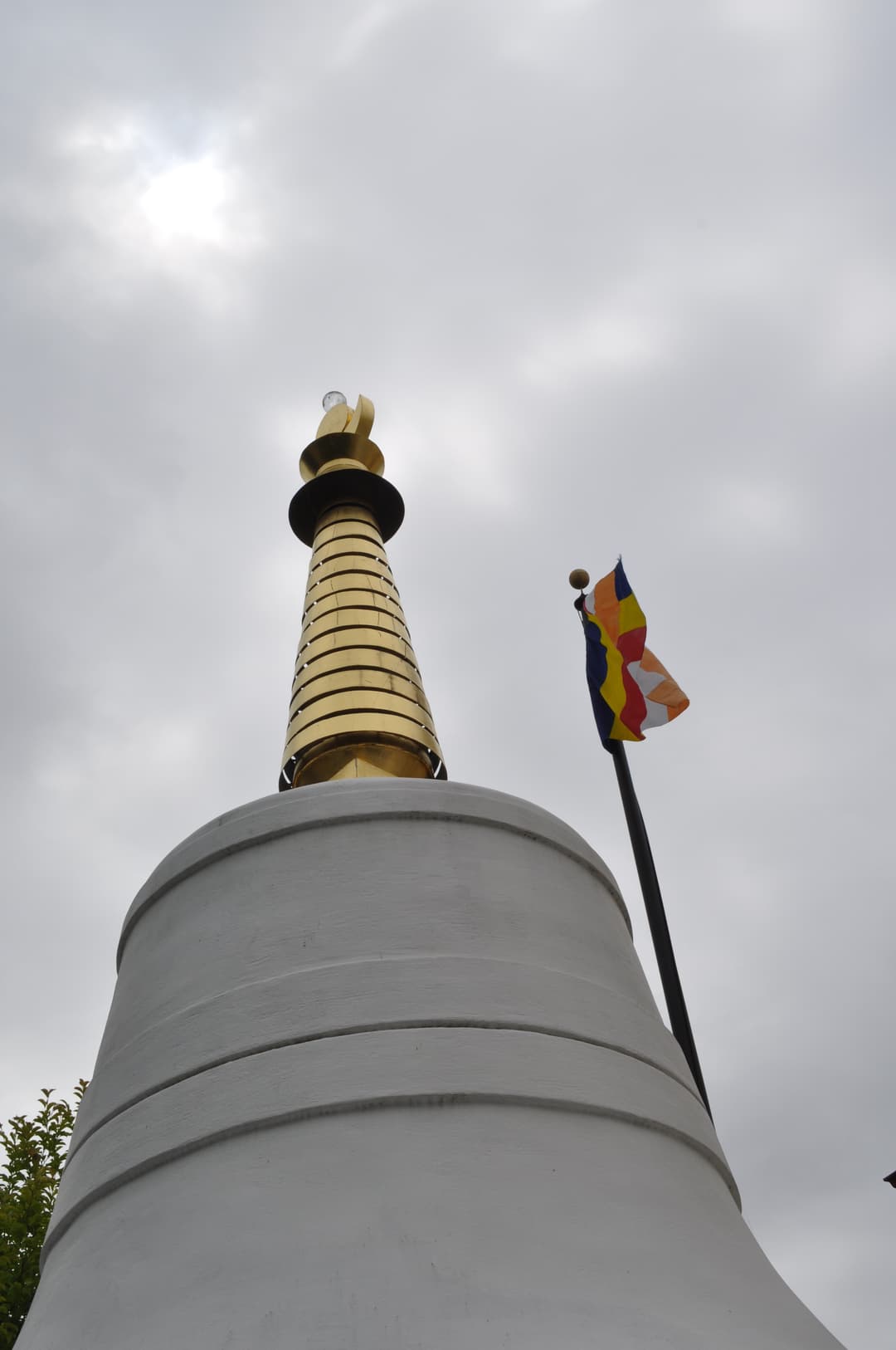 Low-angle view of the stupa dome and golden spire with Buddhist flag.