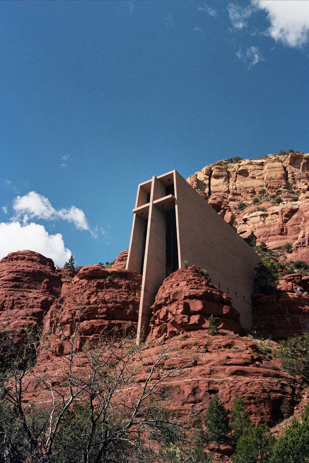 Low-angle view of the Chapel of the Holy Cross embedded in red rock cliffs.