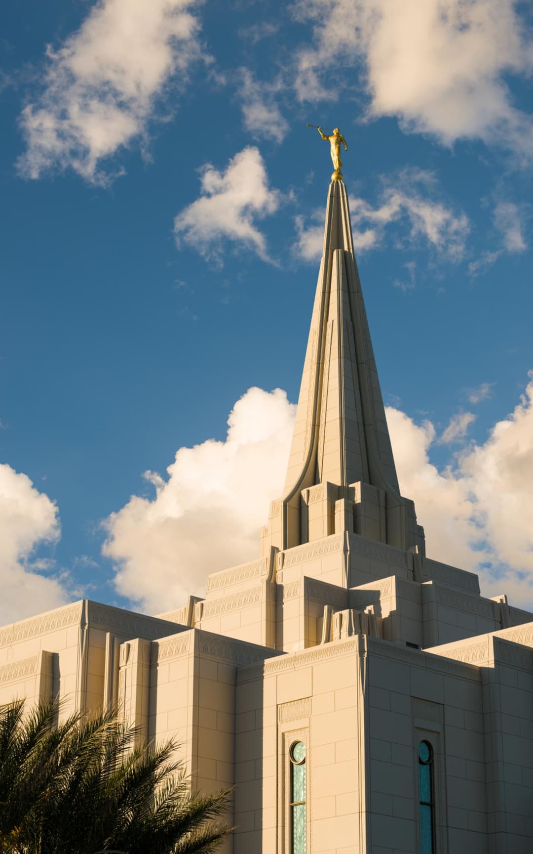 Gilbert Arizona Temple spire and Angel Moroni under warm, cloudy skies.