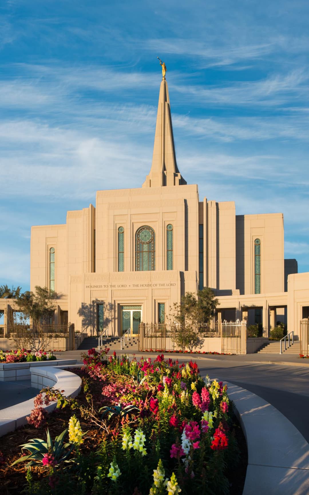 Gilbert Arizona Temple exterior at golden hour with spire, Moroni, and gardens.