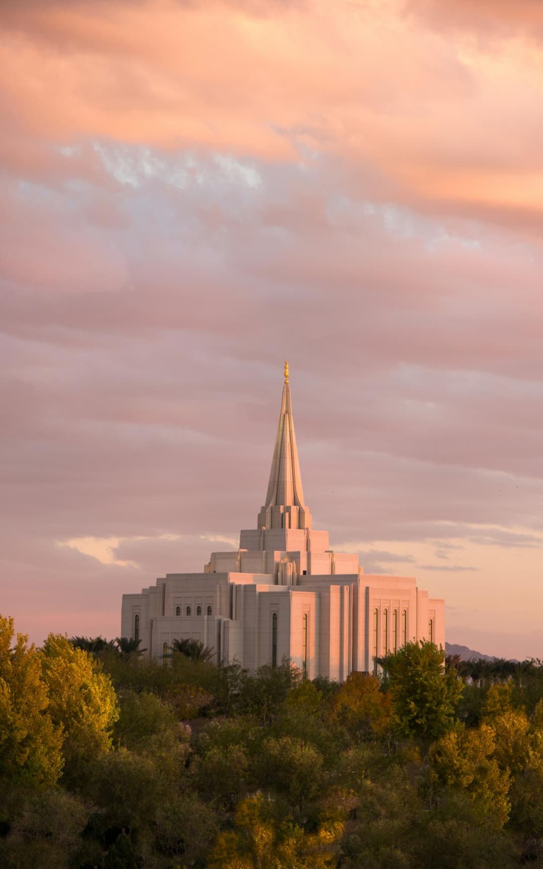 Gilbert Arizona Temple at sunset, with its central spire against pink clouds.
