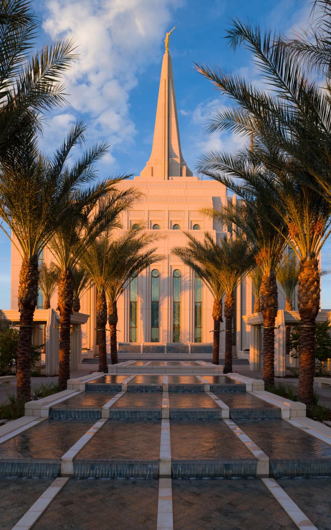 Gilbert Arizona Temple exterior, golden hour, framed by palms and water.