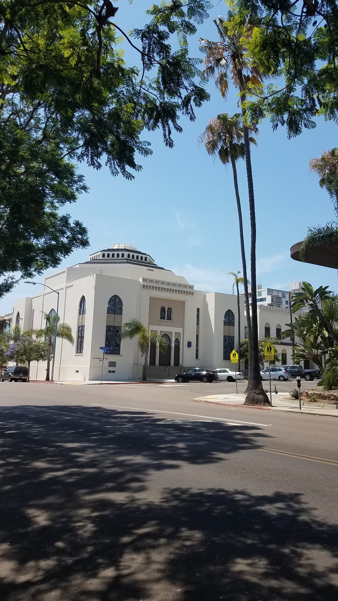 Street view of the temple and central dome framed by trees in daylight.