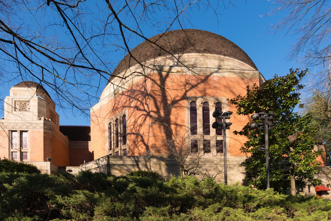 Exterior view of the massive tiled dome and brick facade framed by trees.