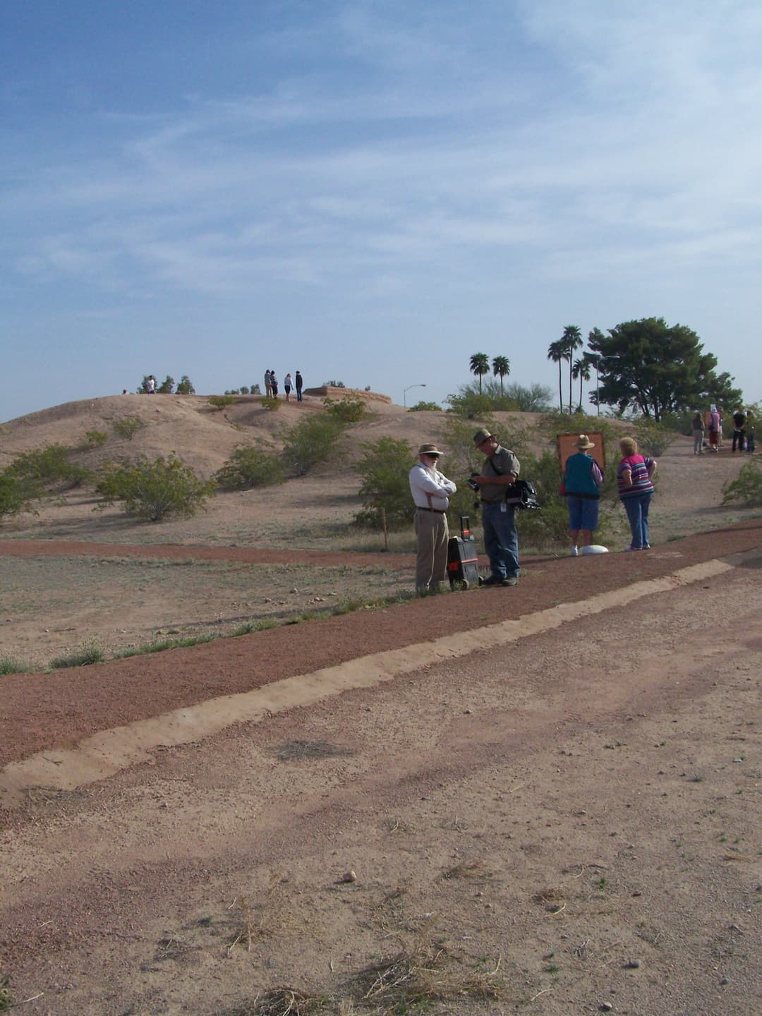 Wide daylight view of the Hohokam platform mound and visitors at Mesa Grande.